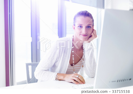 Attractive office worker sitting at desk Attractive office worker sitting at desk 33715538