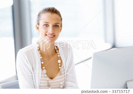 Attractive office worker sitting at desk Attractive office worker sitting at desk 33715717