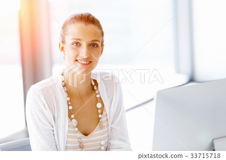 Attractive office worker sitting at desk Attractive office worker sitting at desk 33715718