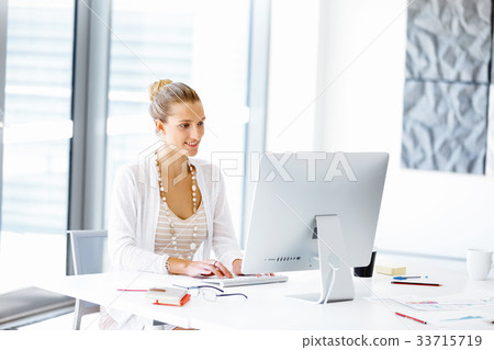 Attractive office worker sitting at desk Attractive office worker sitting at desk 33715719