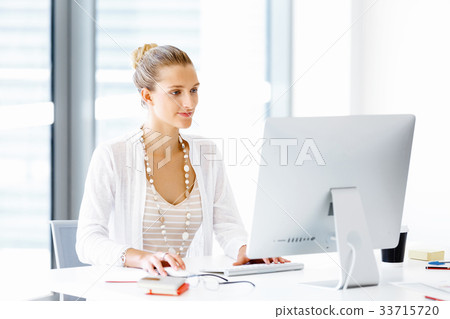 Attractive office worker sitting at desk Attractive office worker sitting at desk 33715720