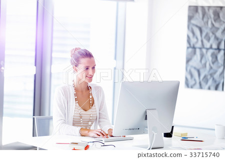 Attractive office worker sitting at desk 33715740