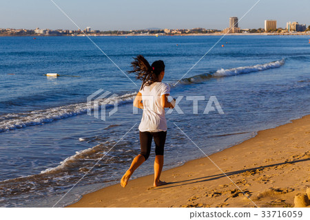 Woman joggingOutdoors on Beach Woman joggingOutdoors on Beach 33716059