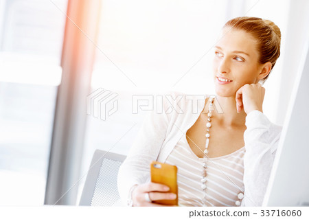 Attractive office worker sitting at desk Attractive office worker sitting at desk 33716060