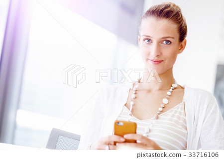 Attractive office worker sitting at desk 33716106