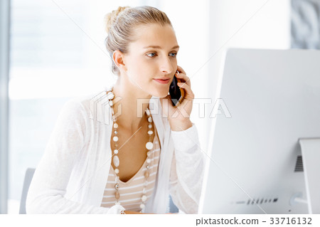 Attractive office worker sitting at desk 33716132