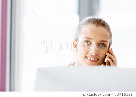 Attractive office worker sitting at desk 33716181