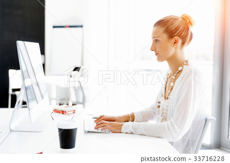 Attractive office worker sitting at desk Attractive office worker sitting at desk 33716228