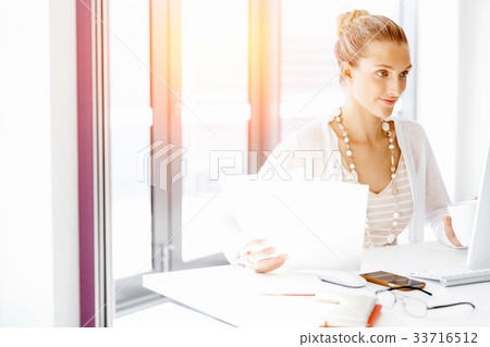 Attractive office worker sitting at desk 33716512