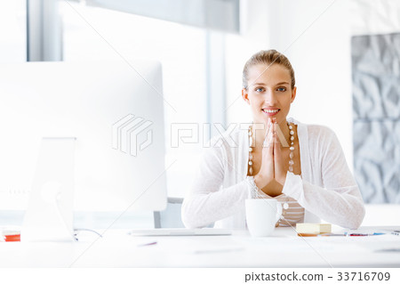Attractive office worker sitting at desk 33716709