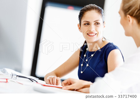 Attractive office worker sitting at desk 33717400