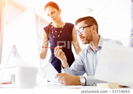 Attractive office worker sitting at desk Attractive office worker sitting at desk 33719043