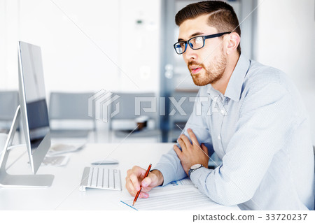 Male office worker sitting at desk Male office worker sitting at desk 33720237