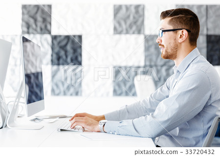 Male office worker sitting at desk Male office worker sitting at desk 33720432