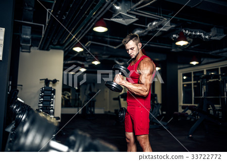 Bodybuilder lifting heavy black dumbbells at the 33722772