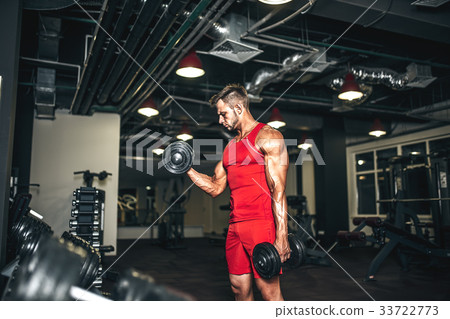 Bodybuilder lifting heavy black dumbbells at the Bodybuilder lifting heavy black dumbbells at the 33722773