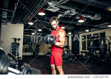 Bodybuilder lifting heavy black dumbbells at the Bodybuilder lifting heavy black dumbbells at the 33722774