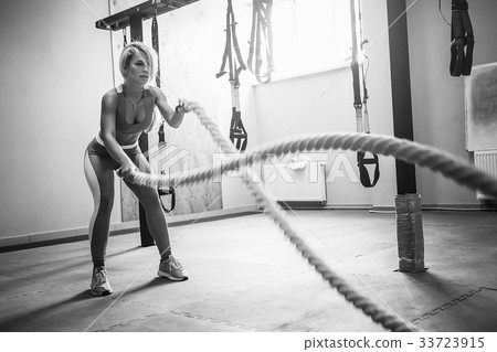 Woman with battle ropes exercise in the fitness 33723915