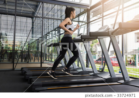 Fitness woman running on running machine at gym 33724971