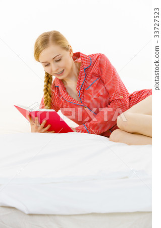 Woman relaxing in bed reading book Woman relaxing in bed reading book 33727523