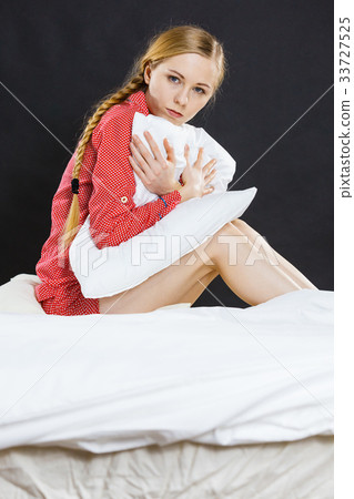 Sad depressed girl in bed gripping pillow Sad depressed girl in bed gripping pillow 33727525