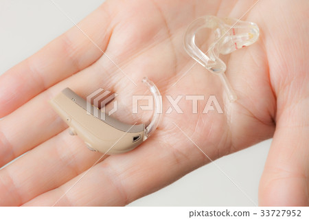 senior person holding hearing aid closeup 33727952