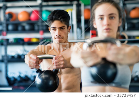 Young fit couple in gym exercising with kettlebell 33729457