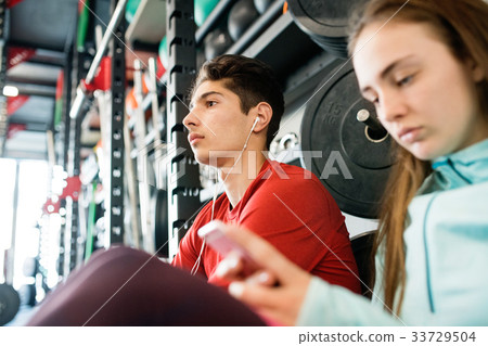 Fit couple in modern crossfit gym with smartphone. 33729504