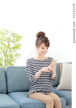 A woman relaxing on a sofa · Smartphone 33732376