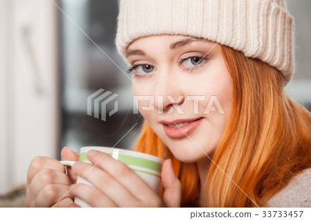 Woman wearing warm clothing and drinking hot drink 33733457