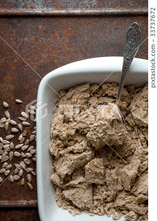 Pieces of halva in a bowl, spoon and seeds on a 33737672