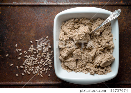 Pieces of halva in a bowl, spoon and seeds on a Pieces of halva in a bowl, spoon and seeds on a 33737674