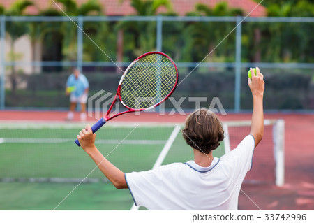 Child playing tennis on outdoor court 33742996