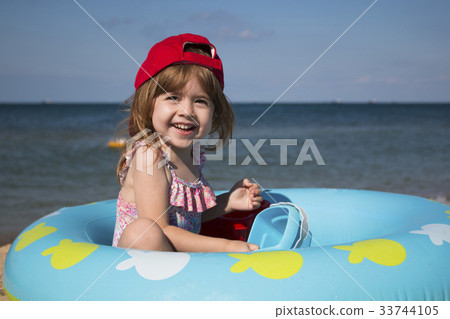 cute little girl in a red cap playing on the beach 33744105