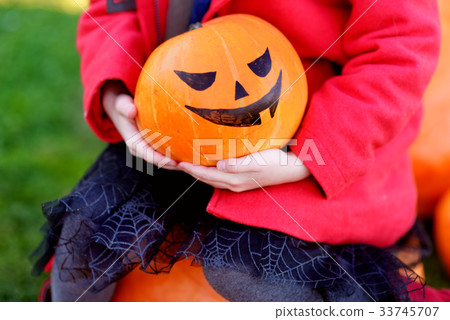 Adorable little girl wearing halloween costume having fun on a pumpkin patch Adorable little girl wearing halloween costume having fun on a pumpkin patch 33745707