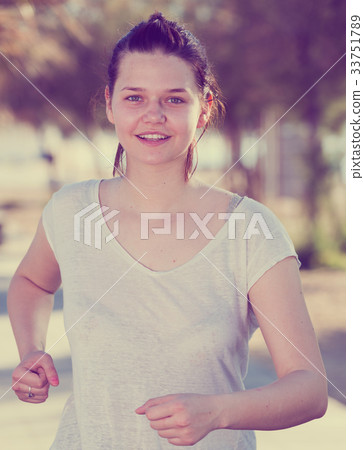 Sportswoman in white T-shirt is jogging 33751789