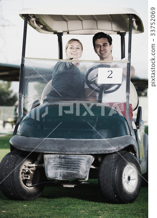 Male and female golf partners using golf cart 33752069