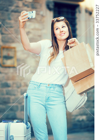 Young female tourist with luggage doing selfie 33752227