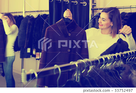 Adult girl deciding on warm brown coat 33752497