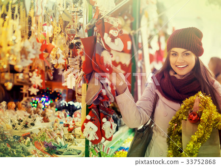 Girl choosing Christmas decoration at market. Girl choosing Christmas decoration at market. 33752868