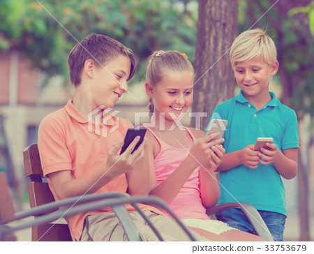 children are chatting in phones in the playground. 33753679