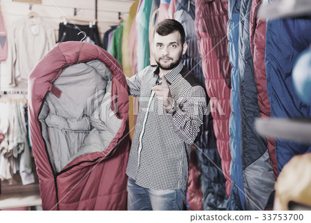 Smiling guy deciding on new sleeping bag 33753700