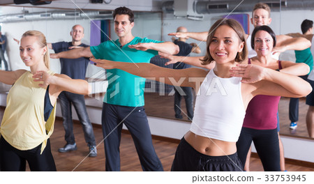 Positive people exercising zumba elements in dancing hall Positive people exercising zumba elements in dancing hall 33753945