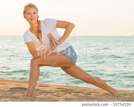 Smiling adult woman in white T-shirt is doing excercises on endurance 33754326