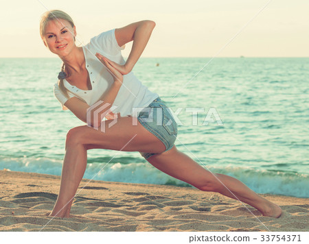 Smiling adult woman in white T-shirt is doing excercises on endurance 33754371