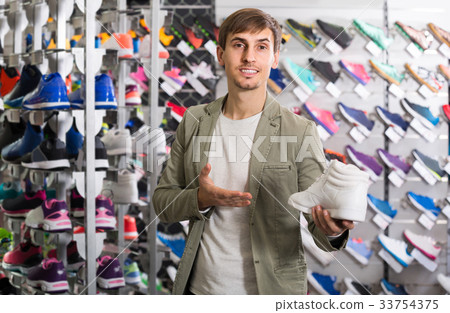 young man showing shoes in the sport store 33754375
