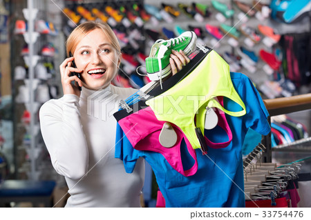Girl picking a sport bra while talking to the phone Girl picking a sport bra while talking to the phone 33754476
