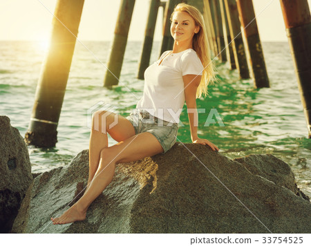 Cheerful female is posing on the rocks in her free time 33754525