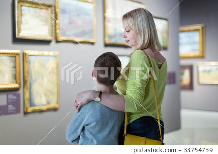Mother and son regarding paintings in halls of museum 33754739
