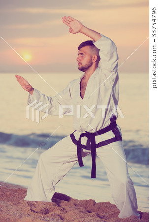 Positive male doing karate at ocean quay Positive male doing karate at ocean quay 33754796